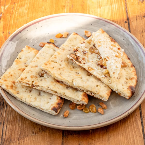 A plate of RaaSa Indian Cuisine's naan bread, some topped with nuts and raisins.