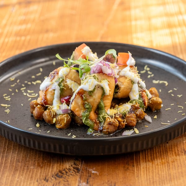RaaSa Indian Cuisine's samosa chaat, topped with yogurt, green chutney, and fresh vegetables.