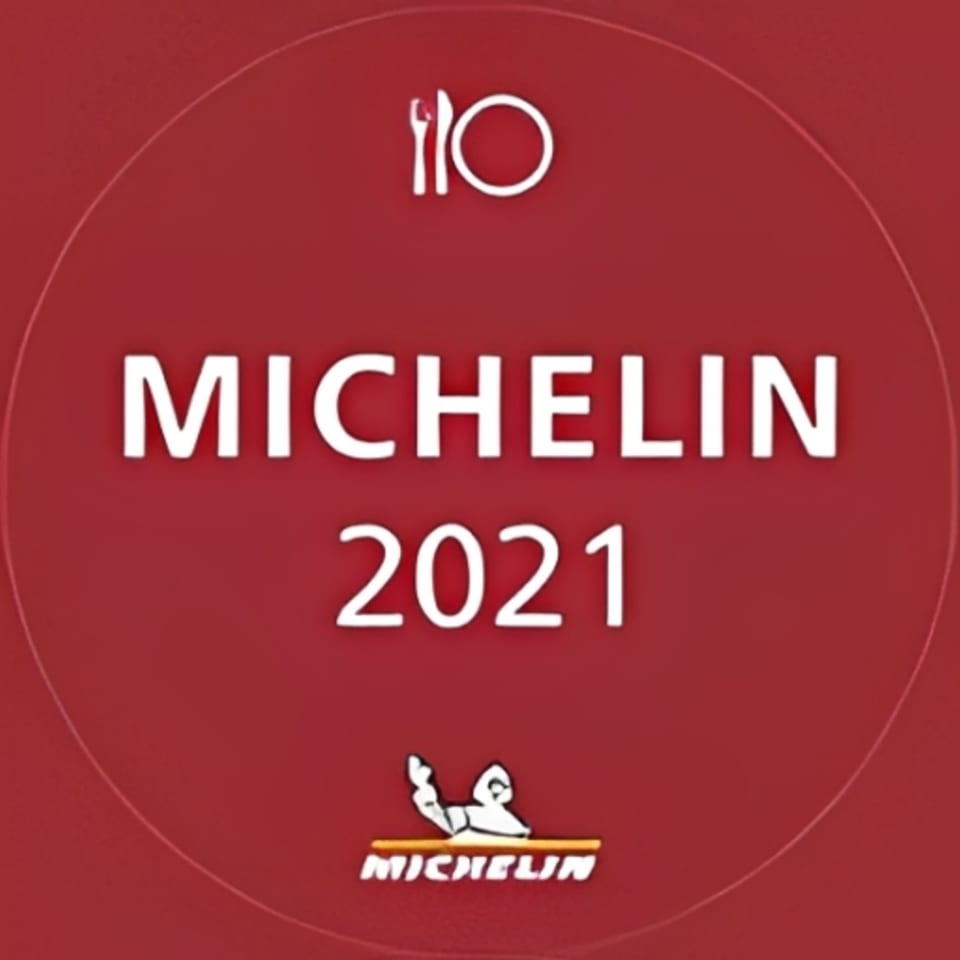 Red circular Michelin Guide 2021 award logo with a plate and cutlery icon.